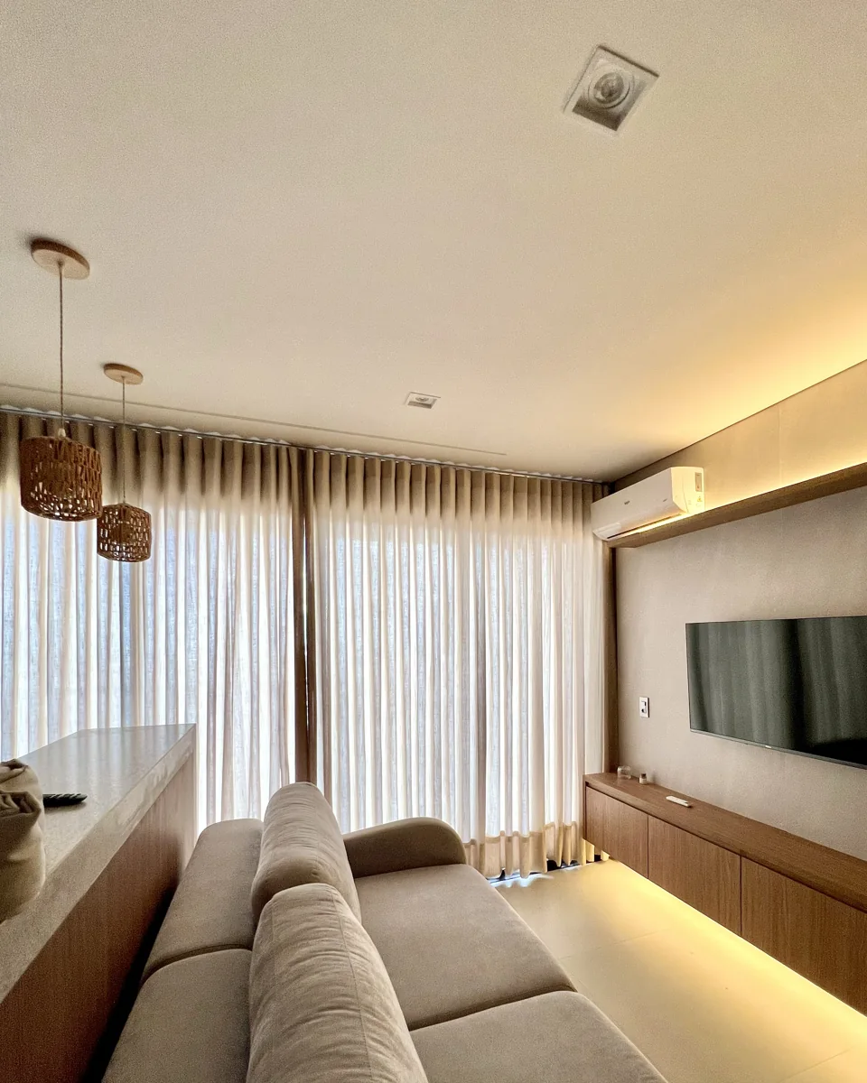 Sala de estar com cortinas de tecido do teto ao piso, sofá e painel de madeira